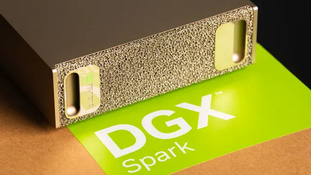 Close-up of the gold front grille of an NVIDIA DGX Spark beside green DGX Spark packaging.