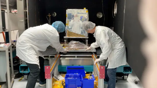 Two technicians position the Suncatcher prototype at a thermal-vacuum chamber during ground testing.